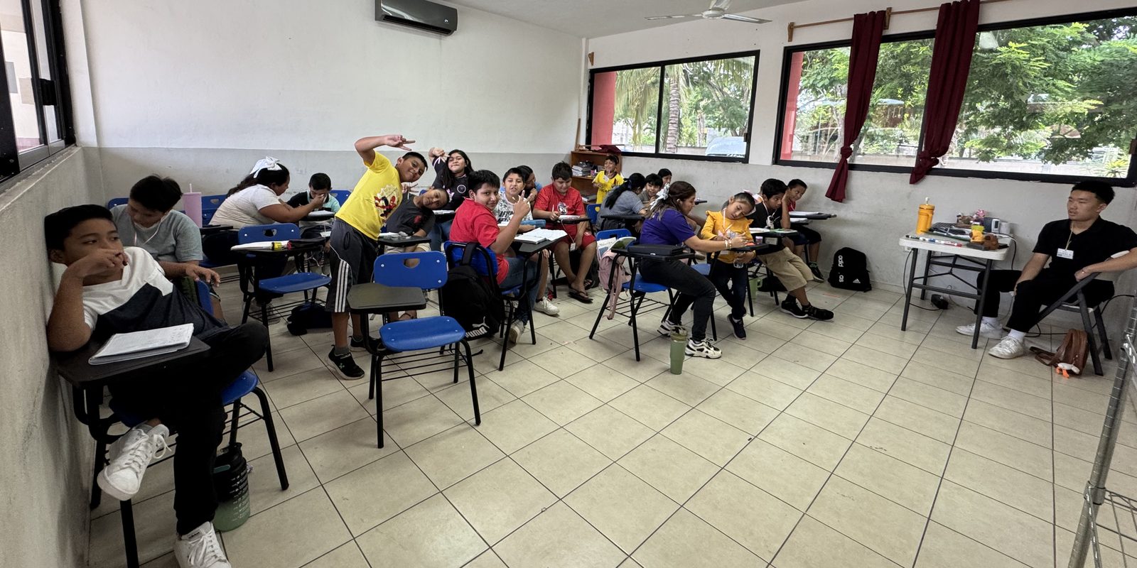 Students at desks during a morning math session in a Yucat&aacute;n classroom, with a BTST volunteer seated at the side